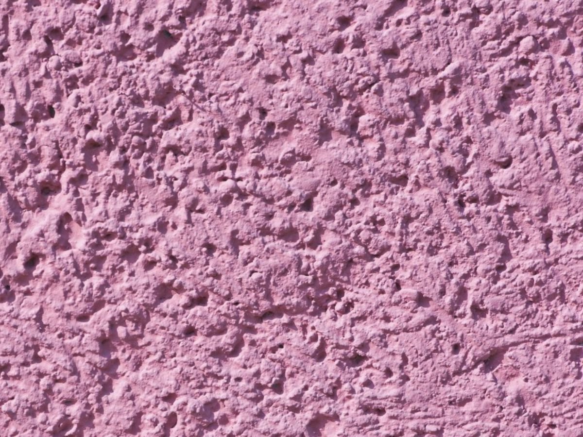 Gros plan d'un crépi rose, grain fort.