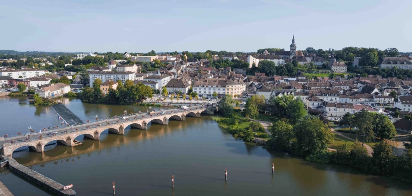 Pont de pierre à arches sur une rivière calme, centre ancien en fond.