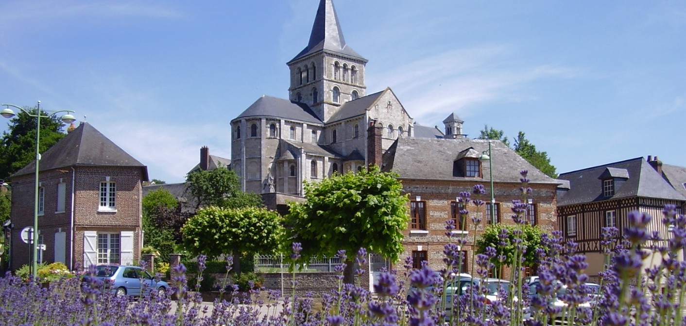 Massif de lavande devant une abbaye en pierre et des maisons en brique.